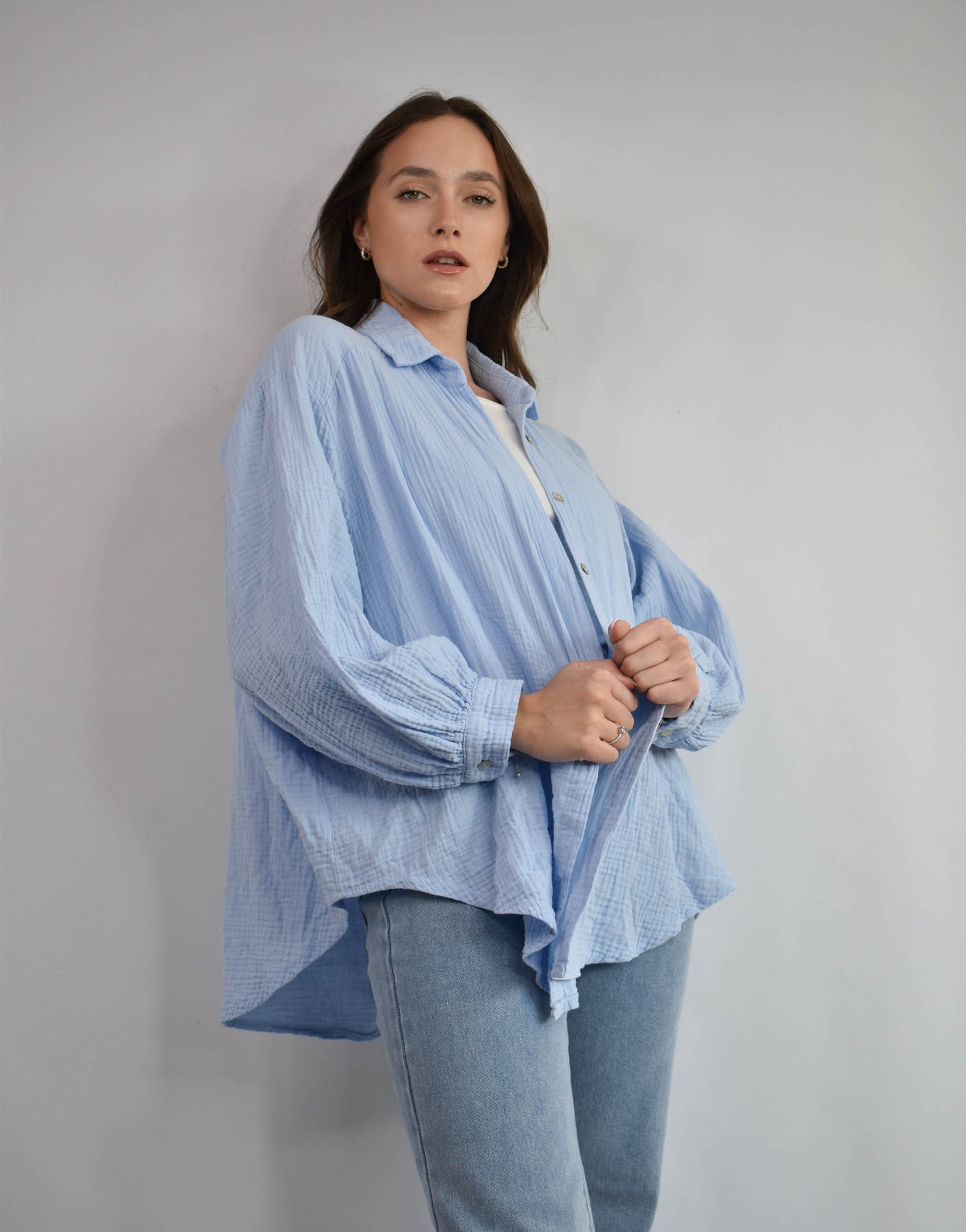 Frau mit brauen Haaren gekleidet in hellblauer Musselin bluse