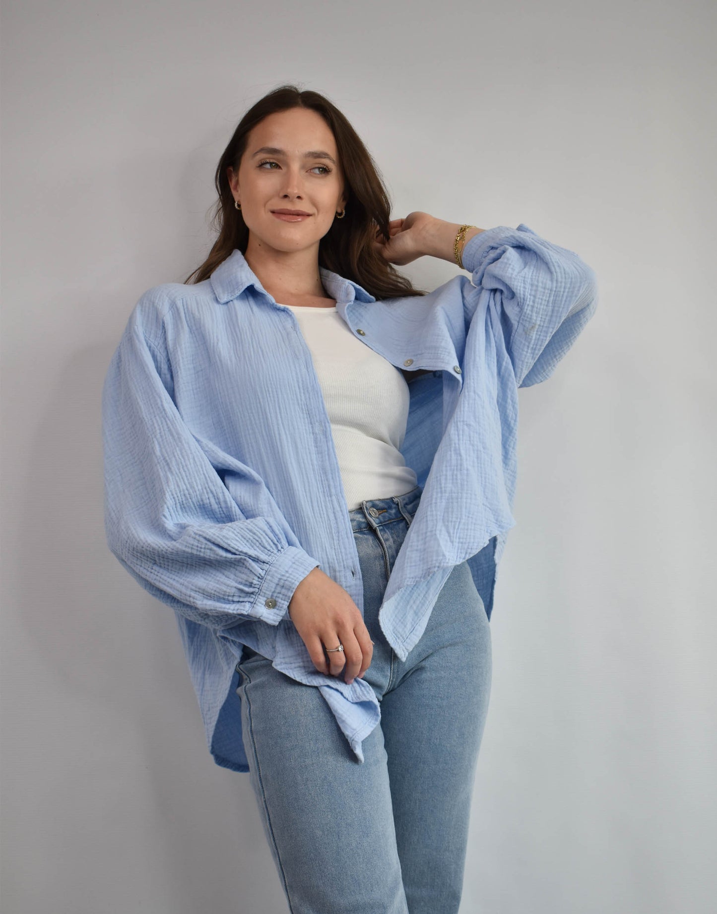 Frau mit brauen Haaren gekleidet in hellblauer Musselin bluse