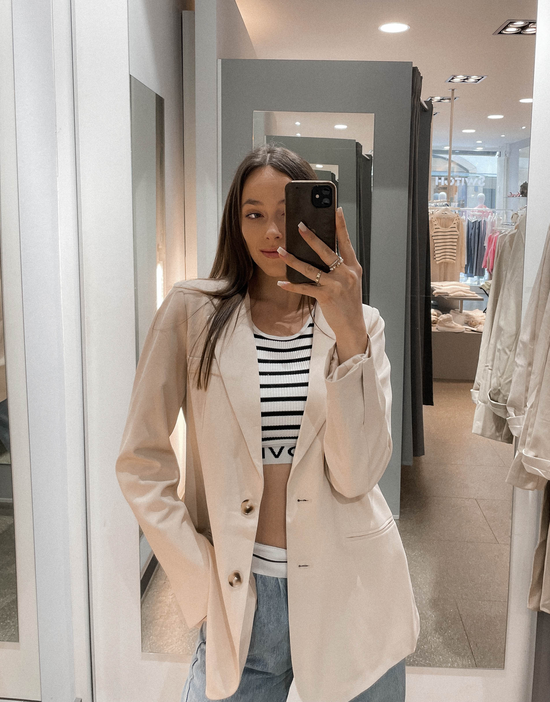Frau mit brauen Haaren trägt kurzes gestreiftes crop top mit einem oversize Blazer