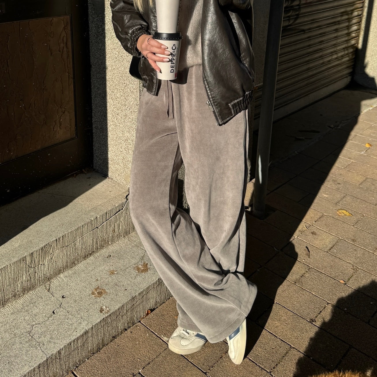 Frau mit brauen Haaren trägt Sreifenhose 