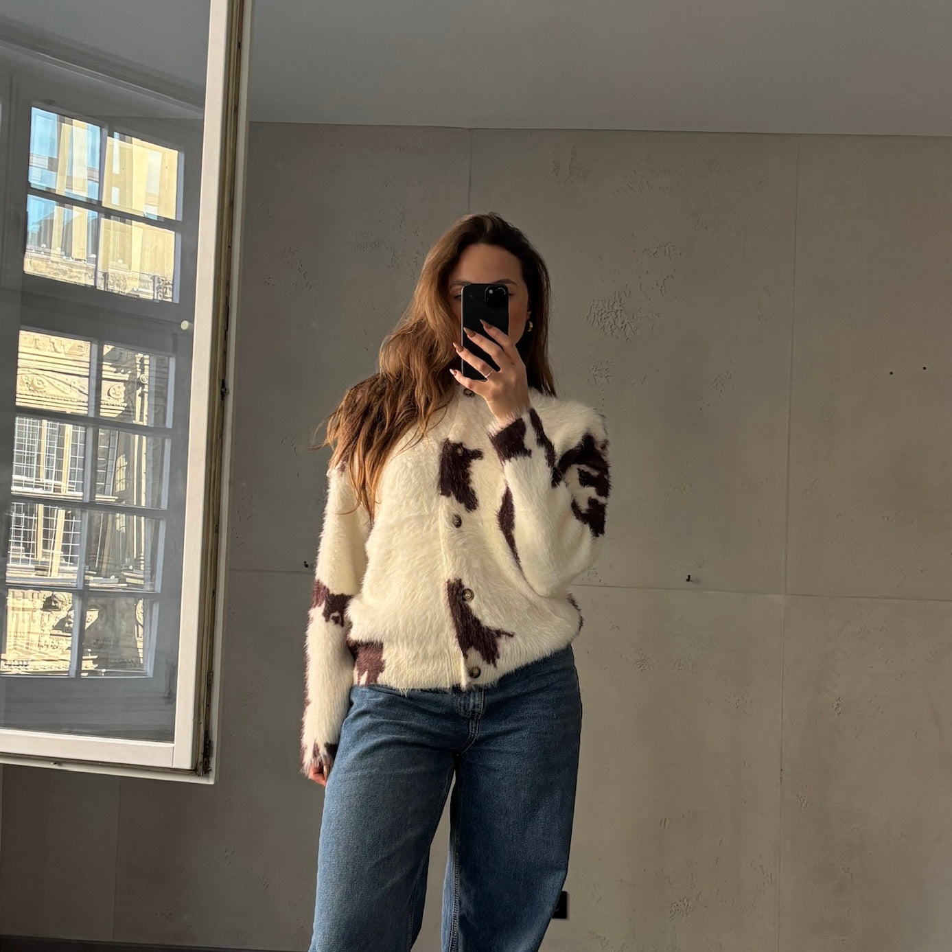 Frau mit brauen Haaren trägt oversize Pullover in beige mit abgesetzter Außennaht in weiß