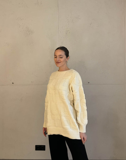 Frau mit brauen Haaren trägt langen Pullover mit Boucle Aufdruck in beige