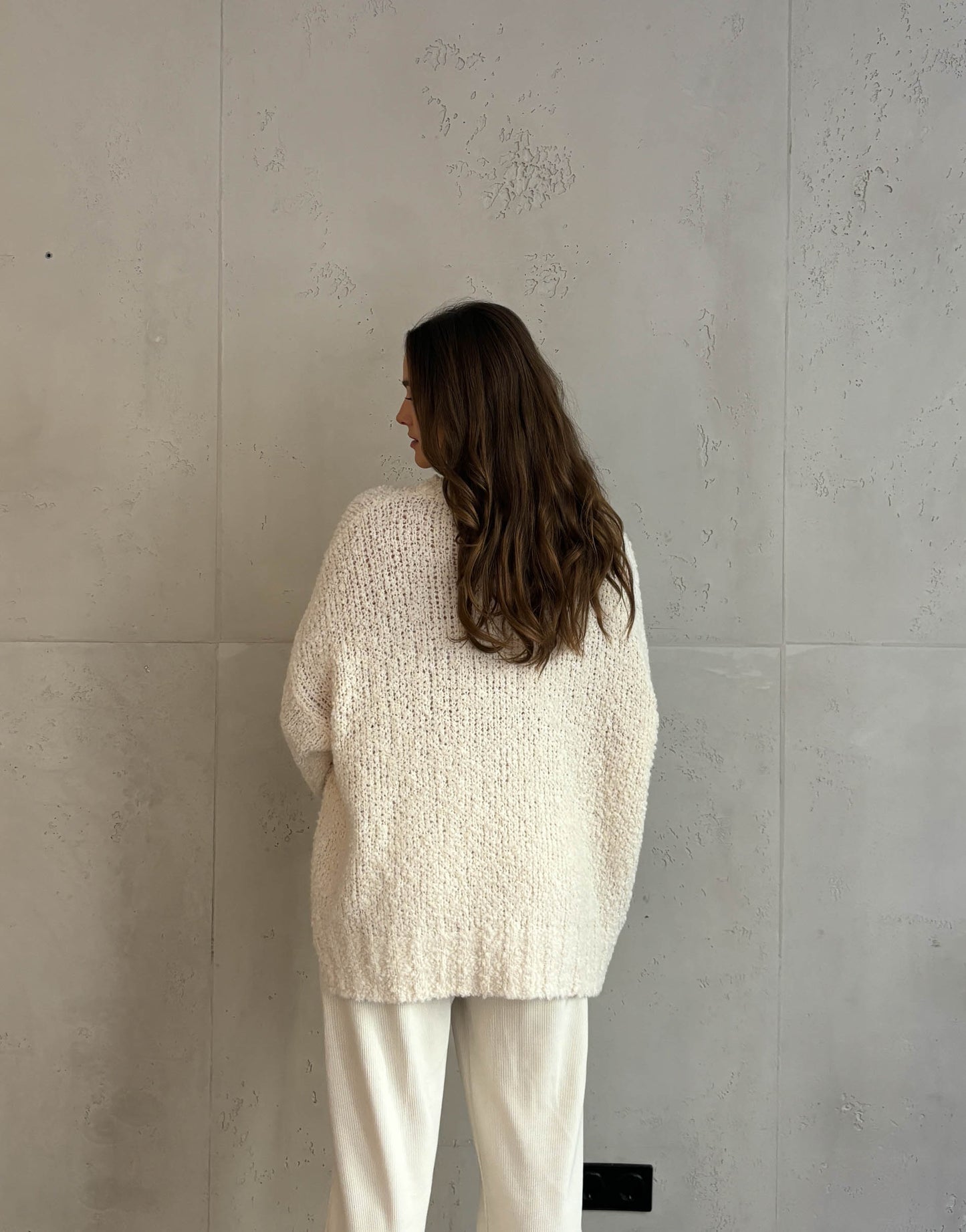 Frau mit braunen Haaren trägt oversize Boucle Pullover in beige 