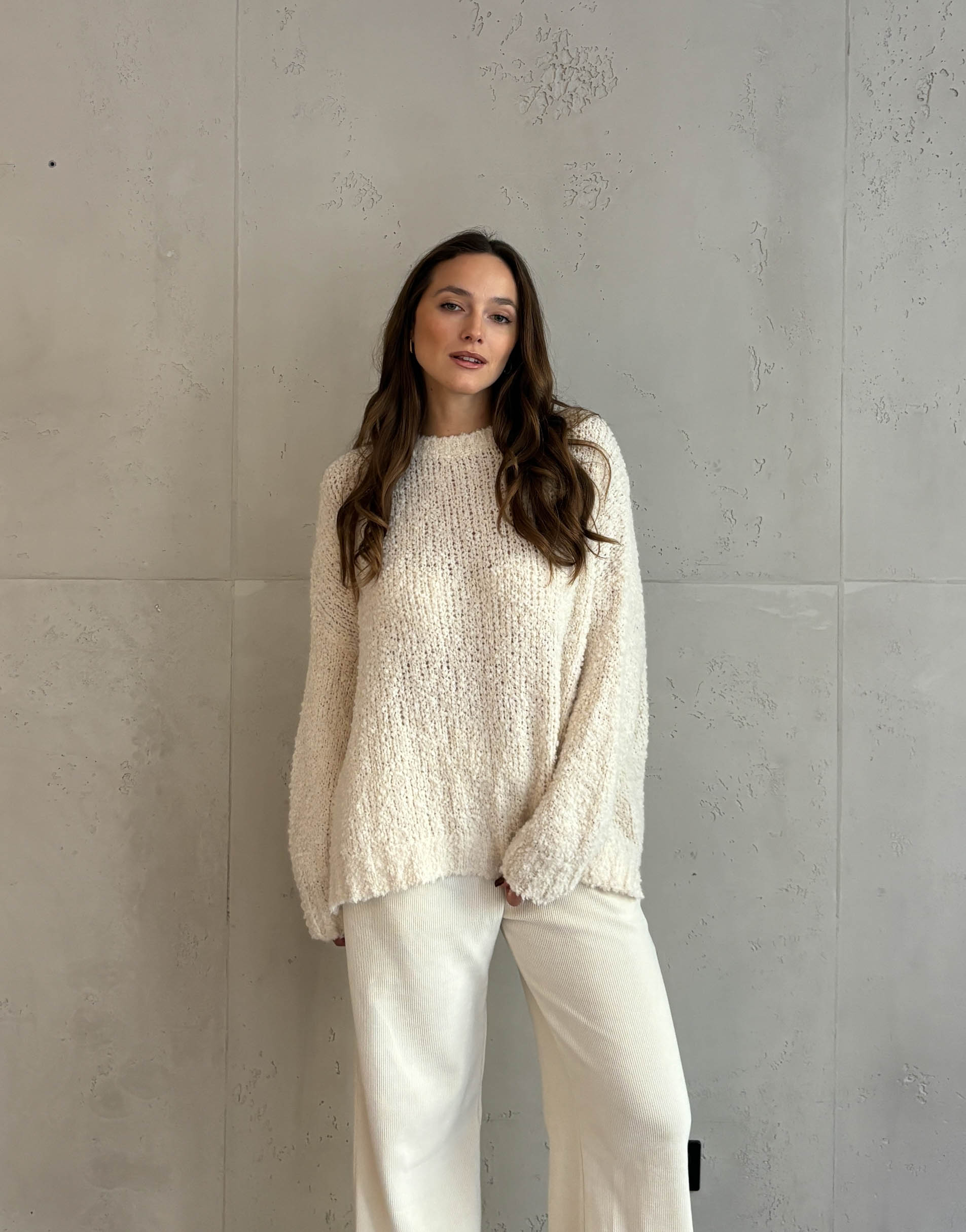 Frau mit braunen Haaren trägt oversize Boucle Pullover in beige 