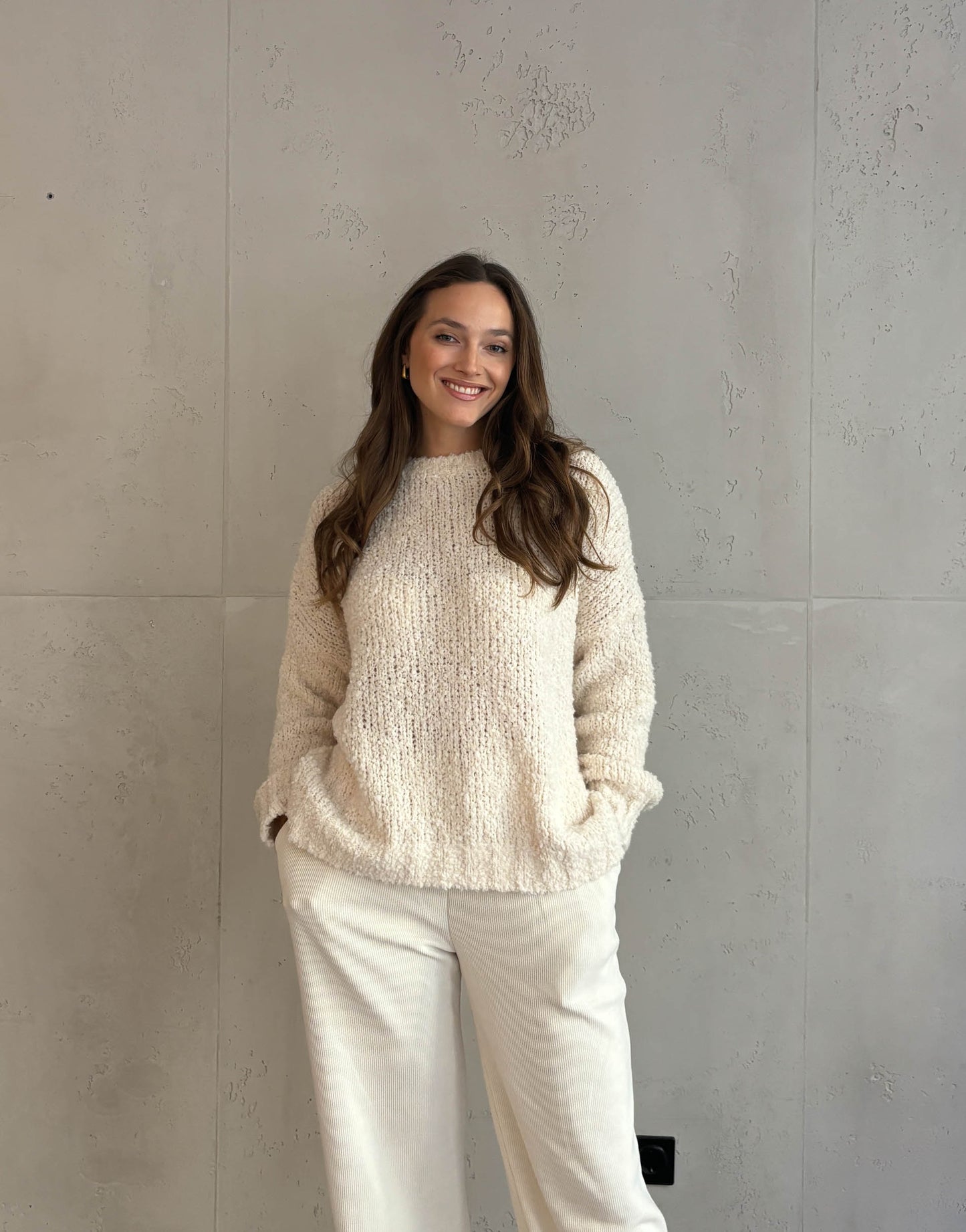 Frau mit braunen Haaren trägt oversize Boucle Pullover in beige 