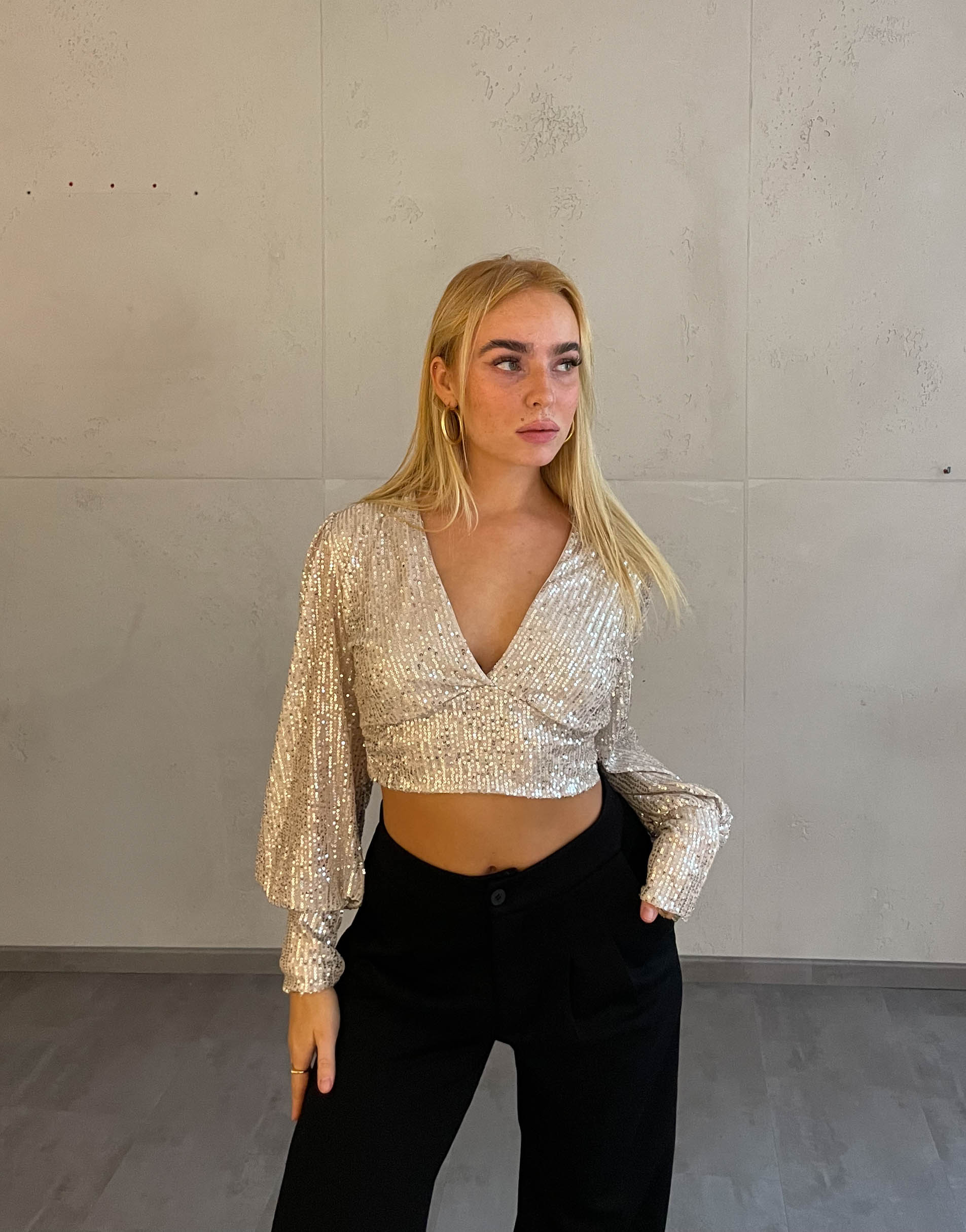 Frau mit blonden Haaren trägt kurzes Paillettenoberteil in Beige