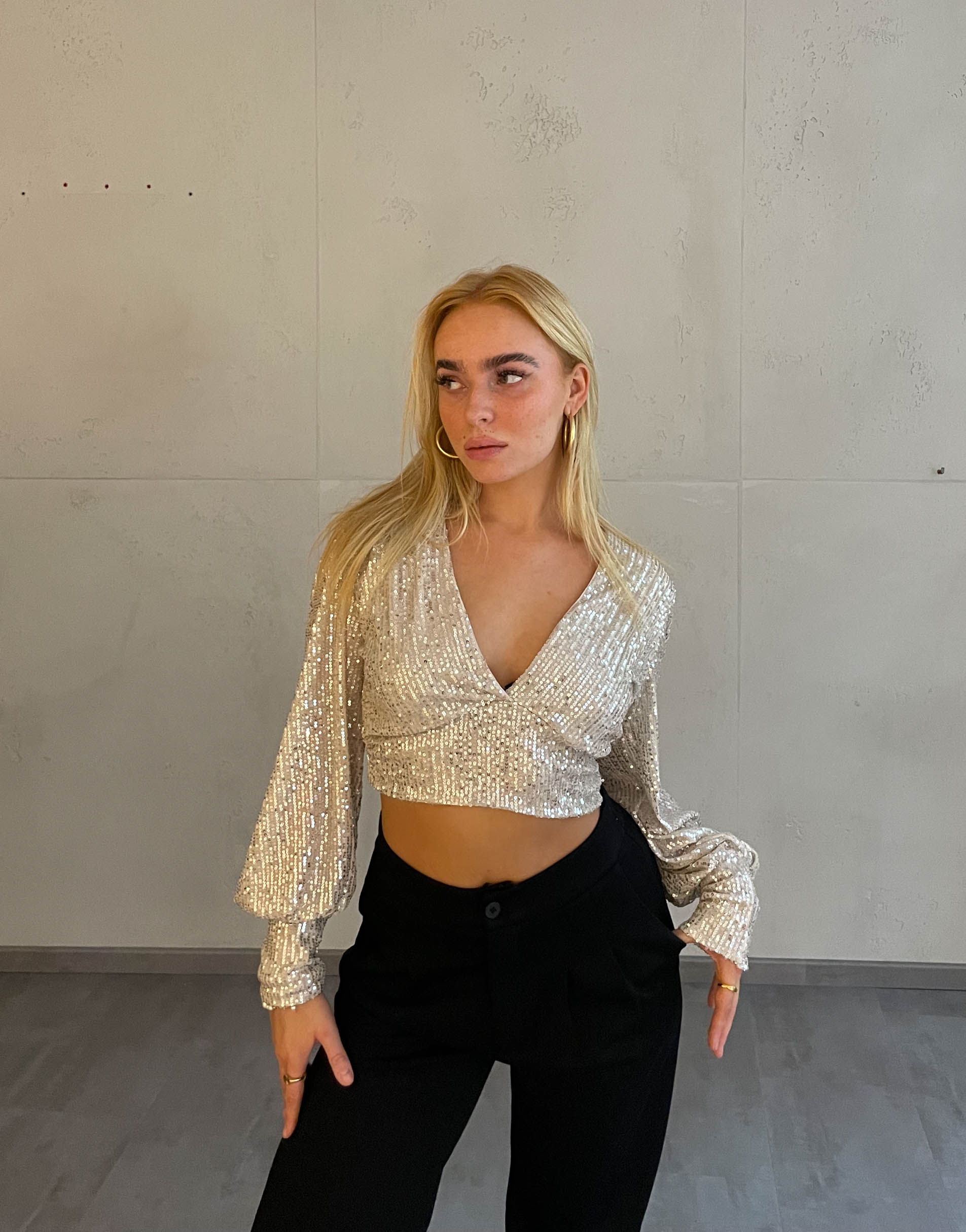 Frau mit blonden Haaren trägt kurzes Paillettenoberteil in Beige