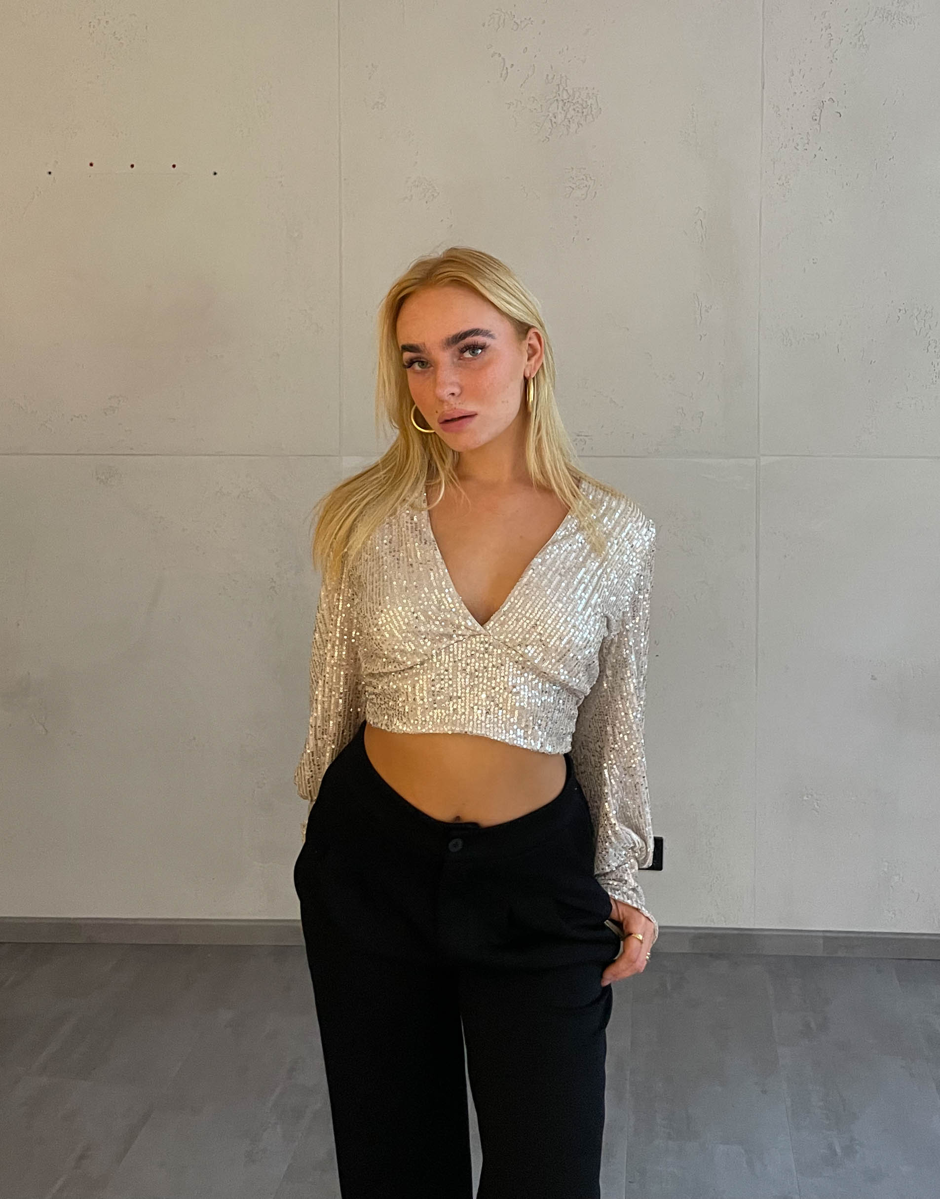 Frau mit blonden Haaren trägt kurzes Paillettenoberteil in Beige
