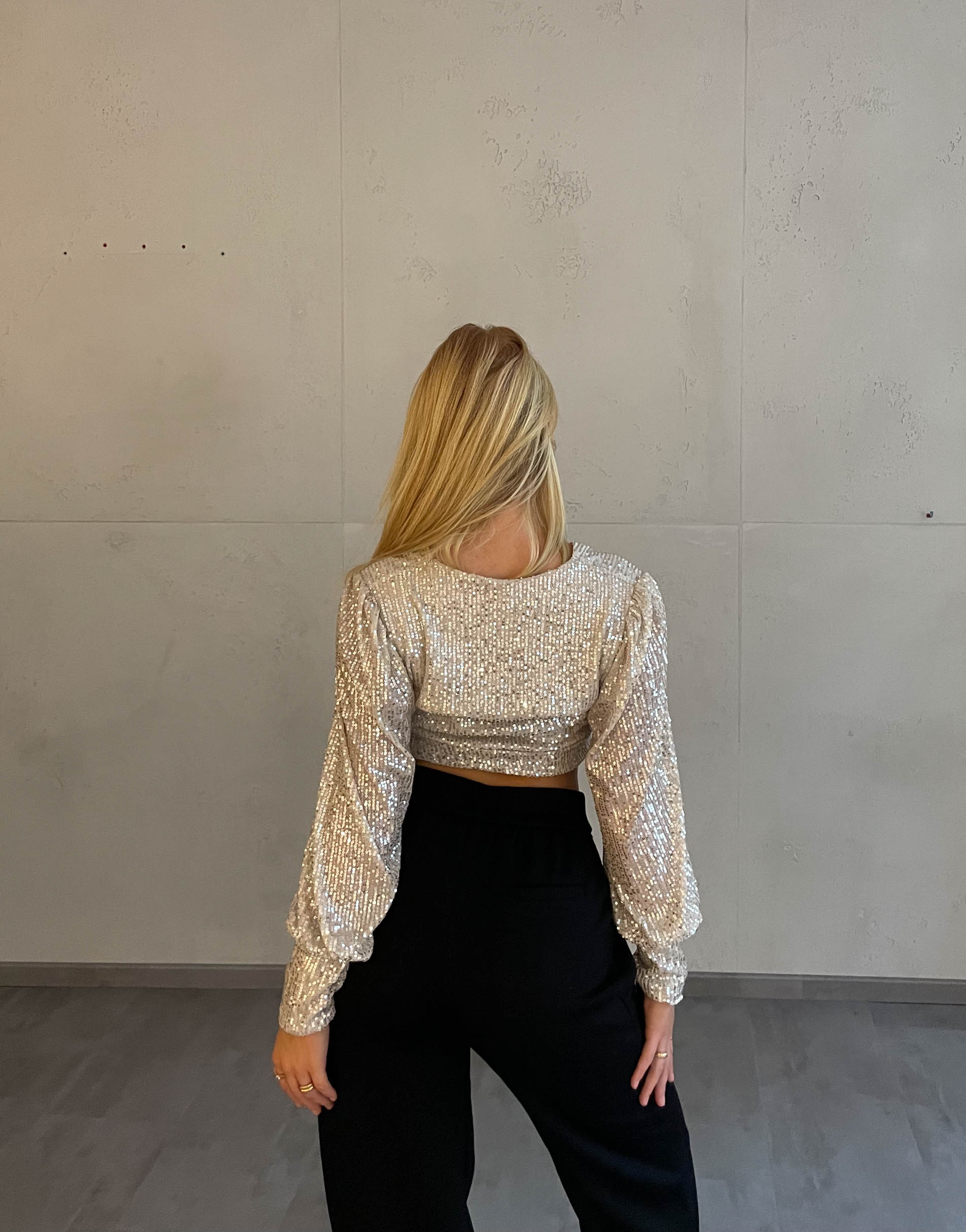 Frau mit blonden Haaren trägt kurzes Paillettenoberteil in Beige