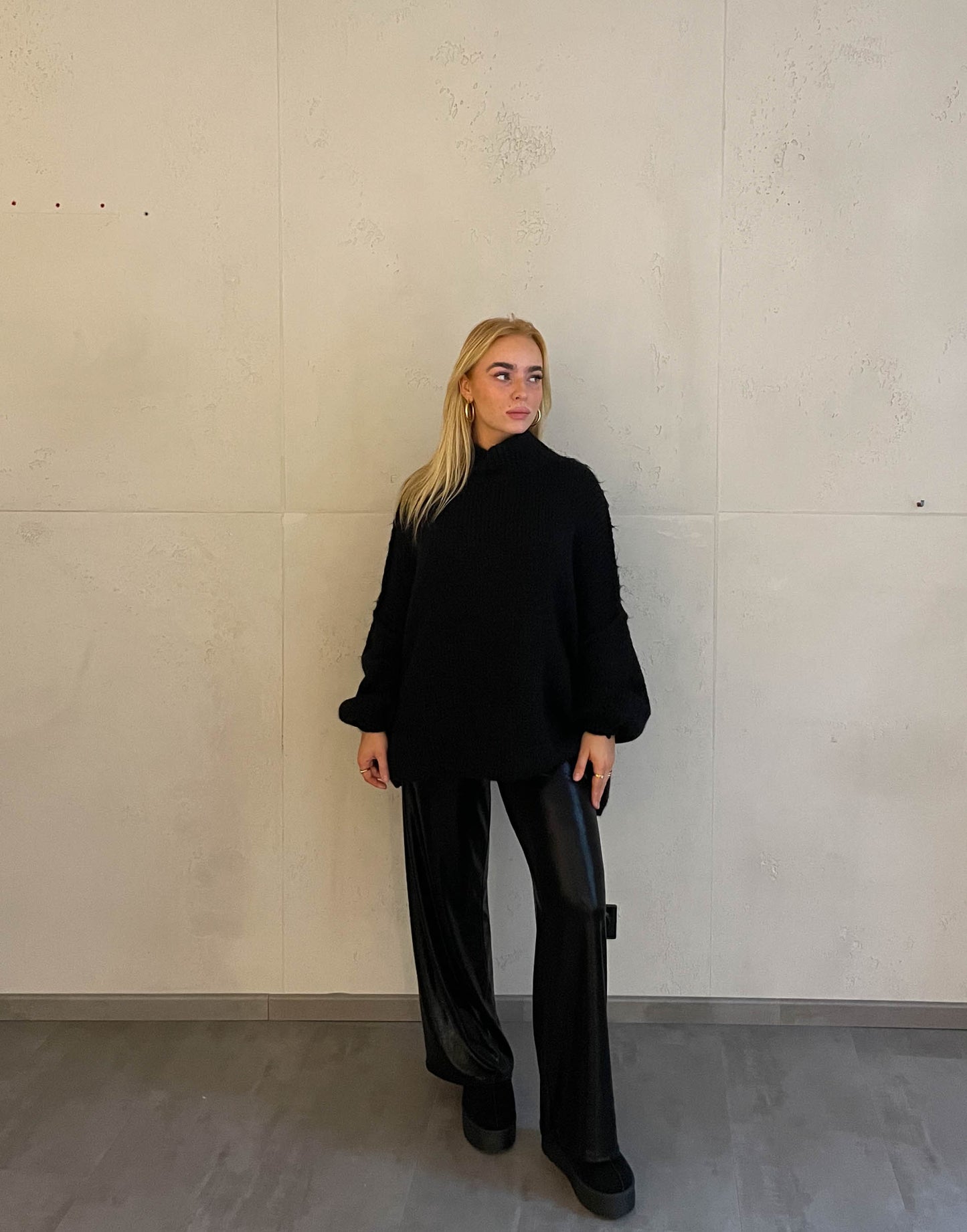Frau mit blonden Haaren trägt Stehkragen Strickpullover in Schwarz