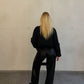 Frau mit blonden Haaren trägt glänzende Hose in Schwarz