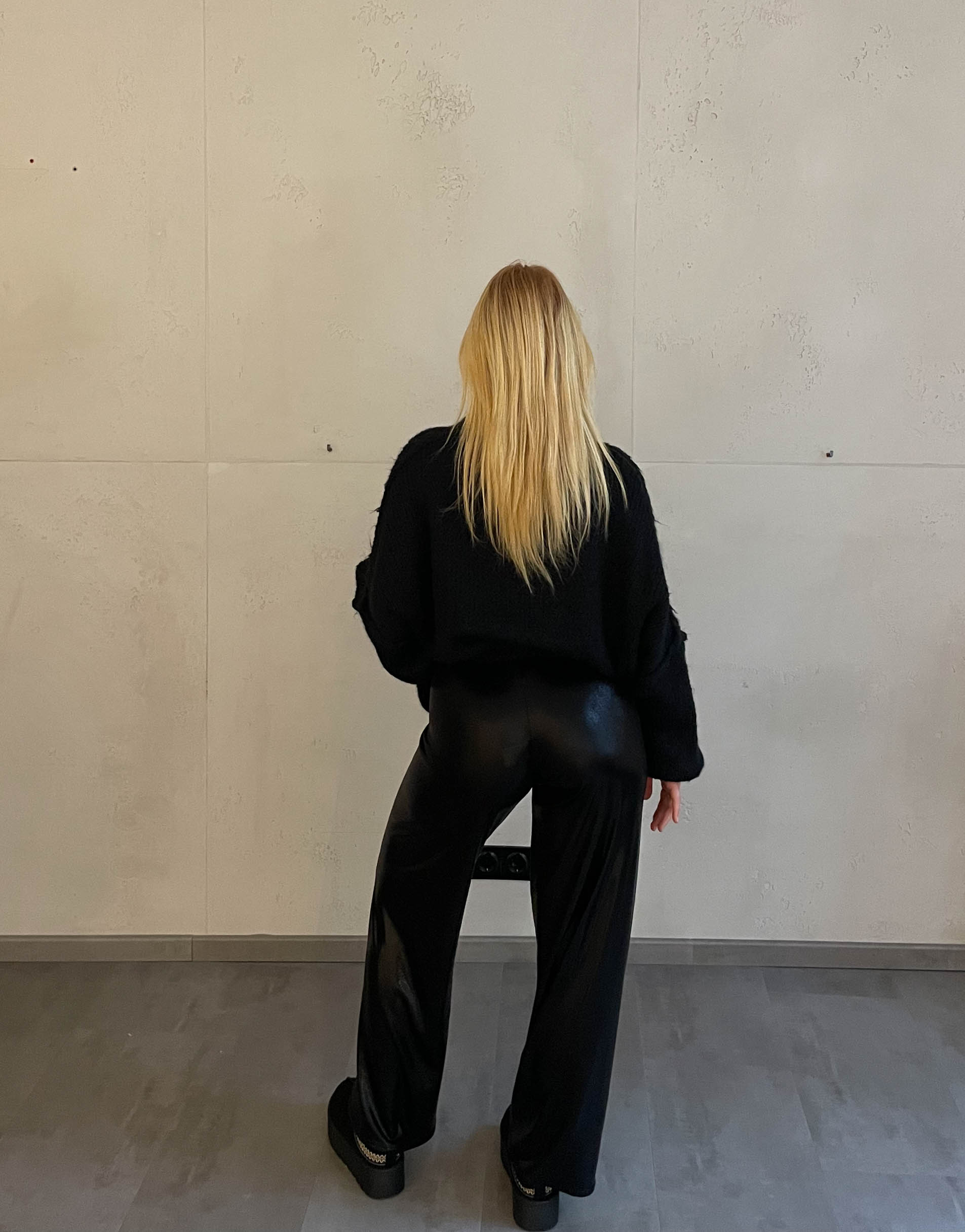 Frau mit blonden Haaren trägt glänzende Hose in Schwarz