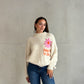 Frau mit braunen Haaren trägt happy vibes Pullover in beige