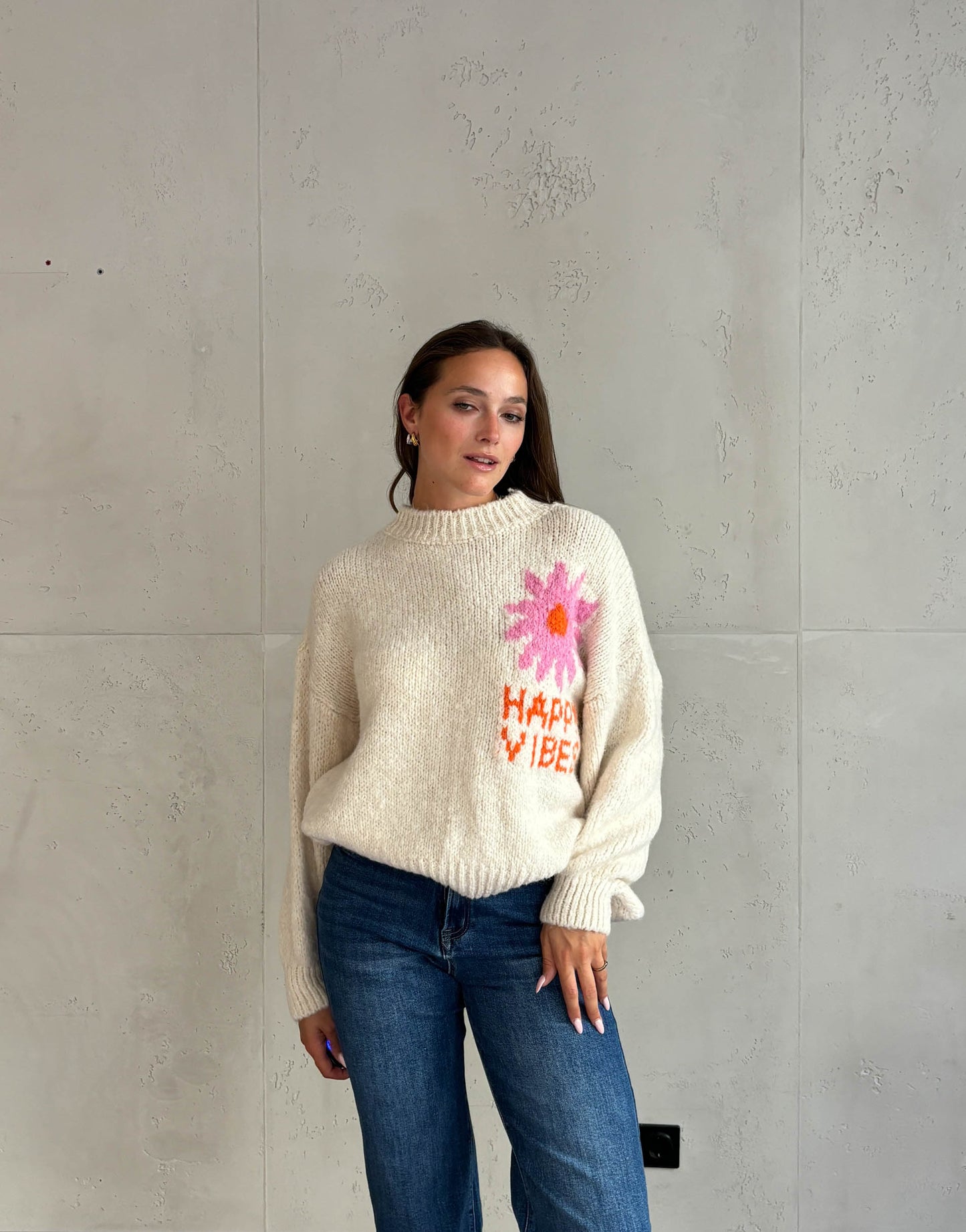 Frau mit braunen Haaren trägt happy vibes Pullover in beige