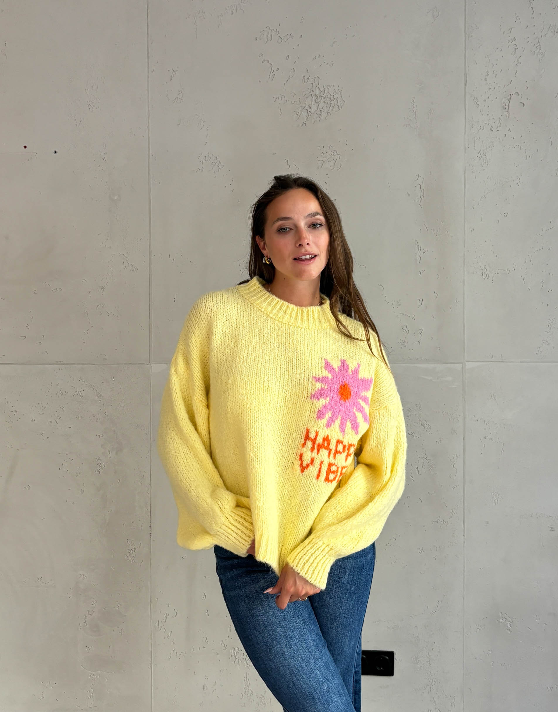 Frau mit braunen Haaren trägt happy vibes Pullover in gelb 