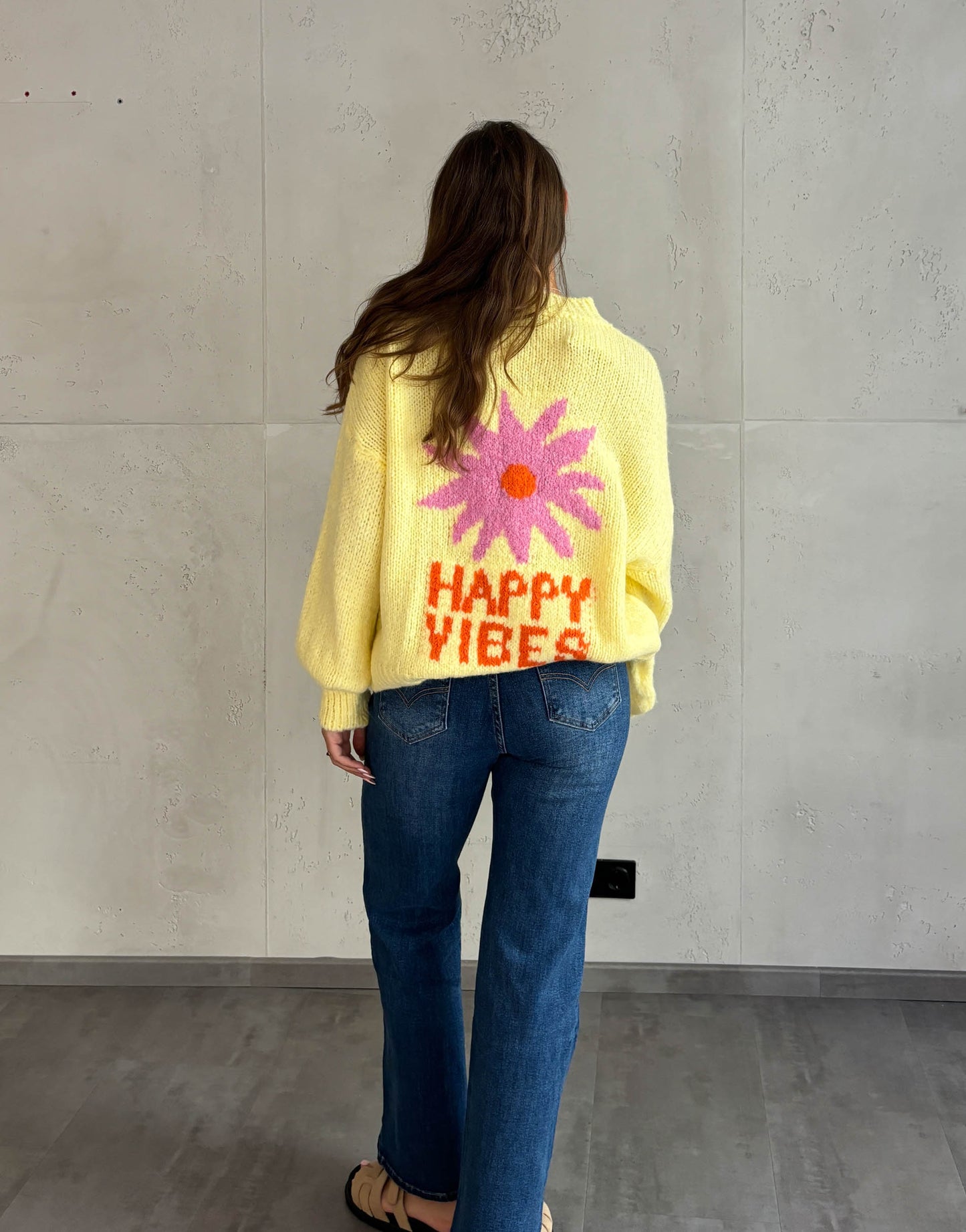 Frau mit braunen Haaren trägt happy vibes Pullover in gelb 