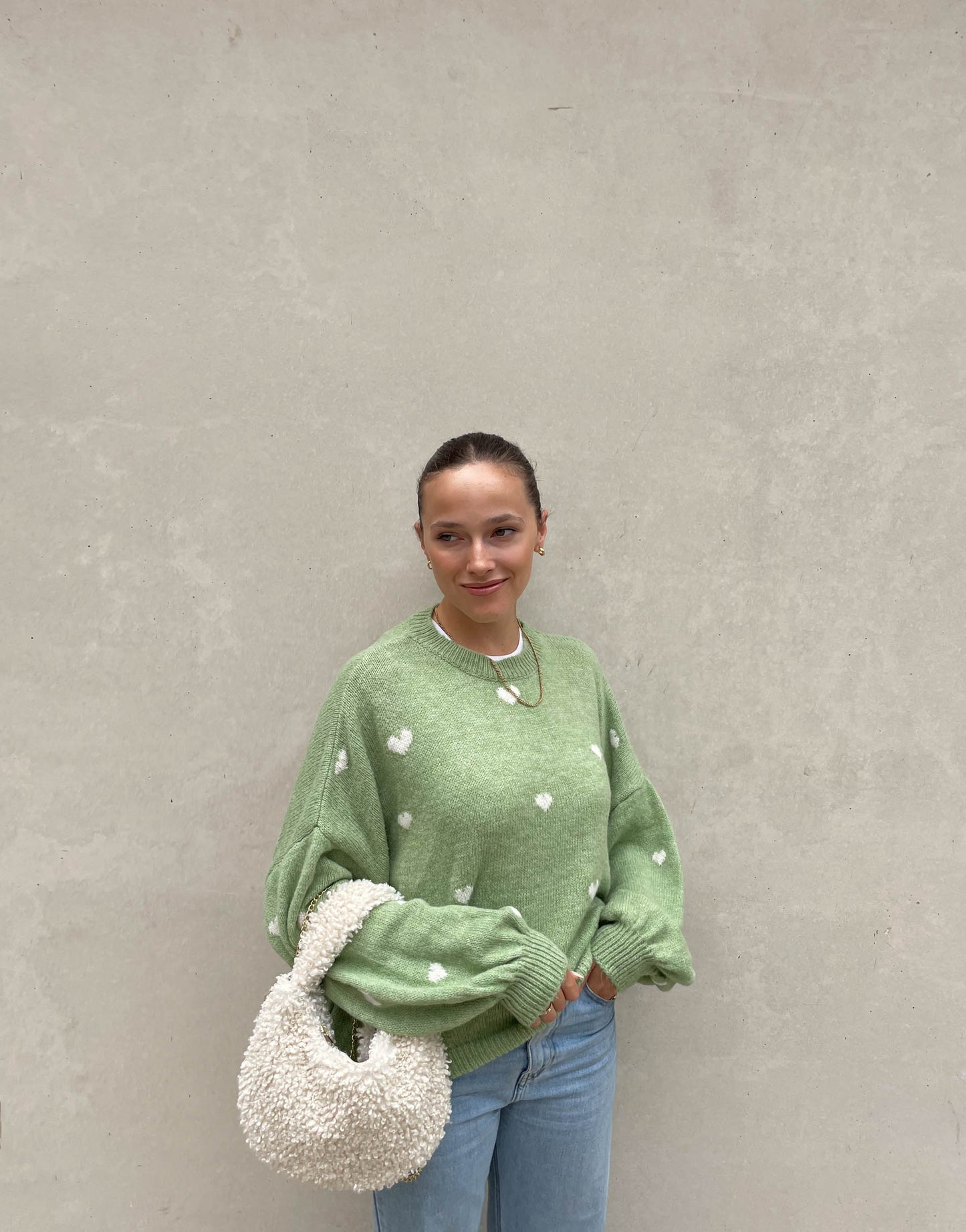 Frau mit brauen Haaren trägt Pullover mit Herzchen in Mint