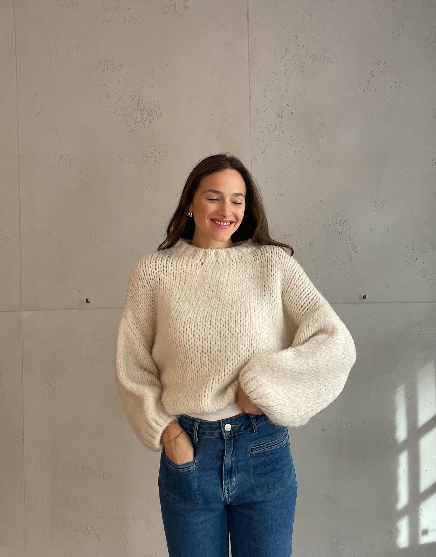 Frau mit brauen Haaren trägt kurzen Grobstrickpullover in hellbeige