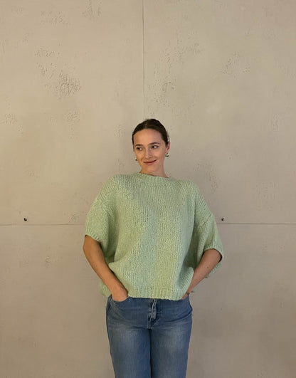 Frau mit brauen Haaren trägt kurzen Wollpullover in mint