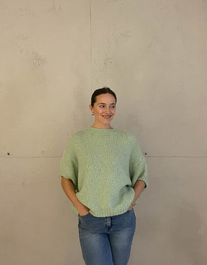 Frau mit brauen Haaren trägt kurzen Wollpullover in mint