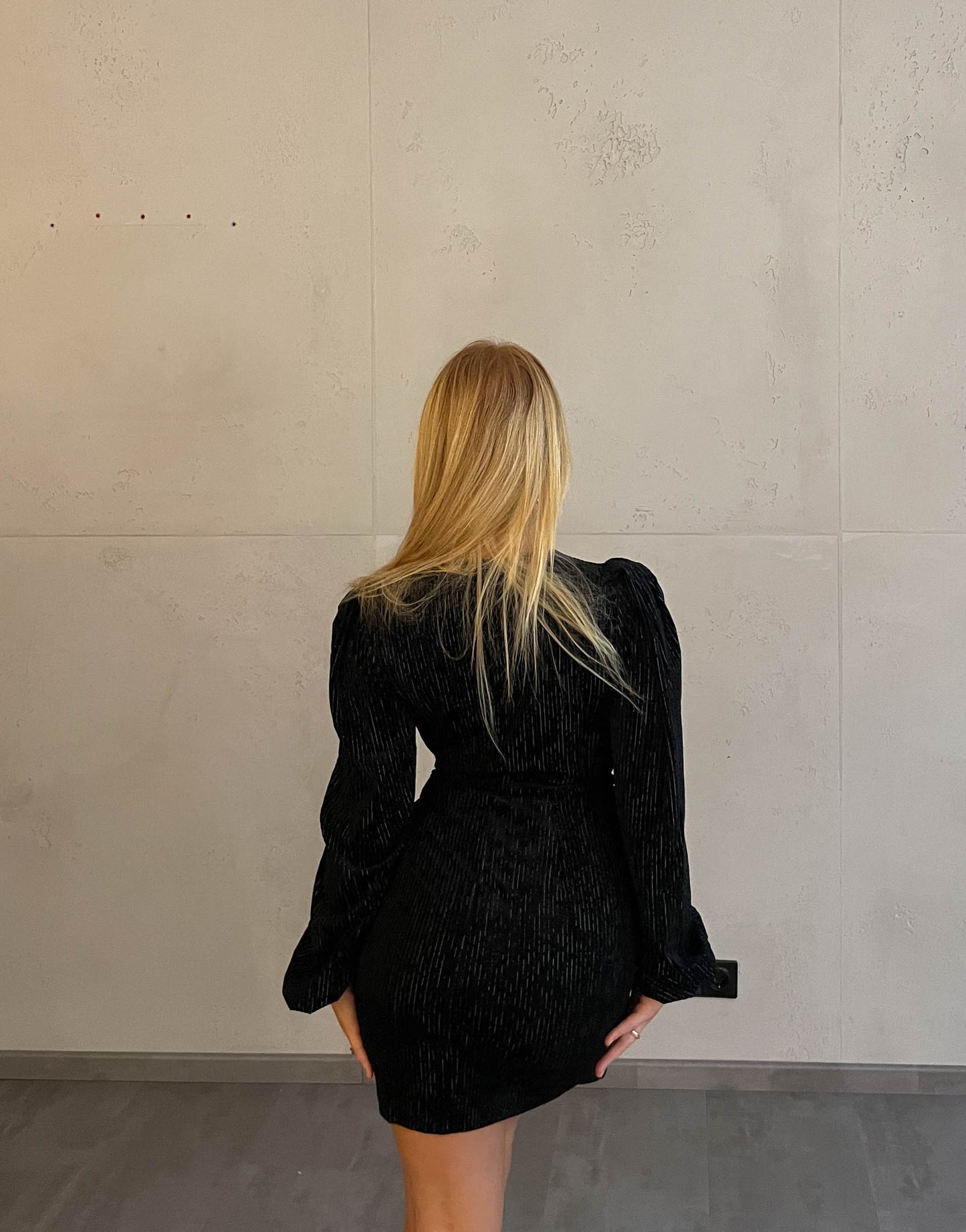 Frau mit blonden Haaren trägt mini Samtkleid in schwarz