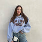Frau mit brauen Haaren trägt oversize Hoodie mit Aufschrift in Grau
