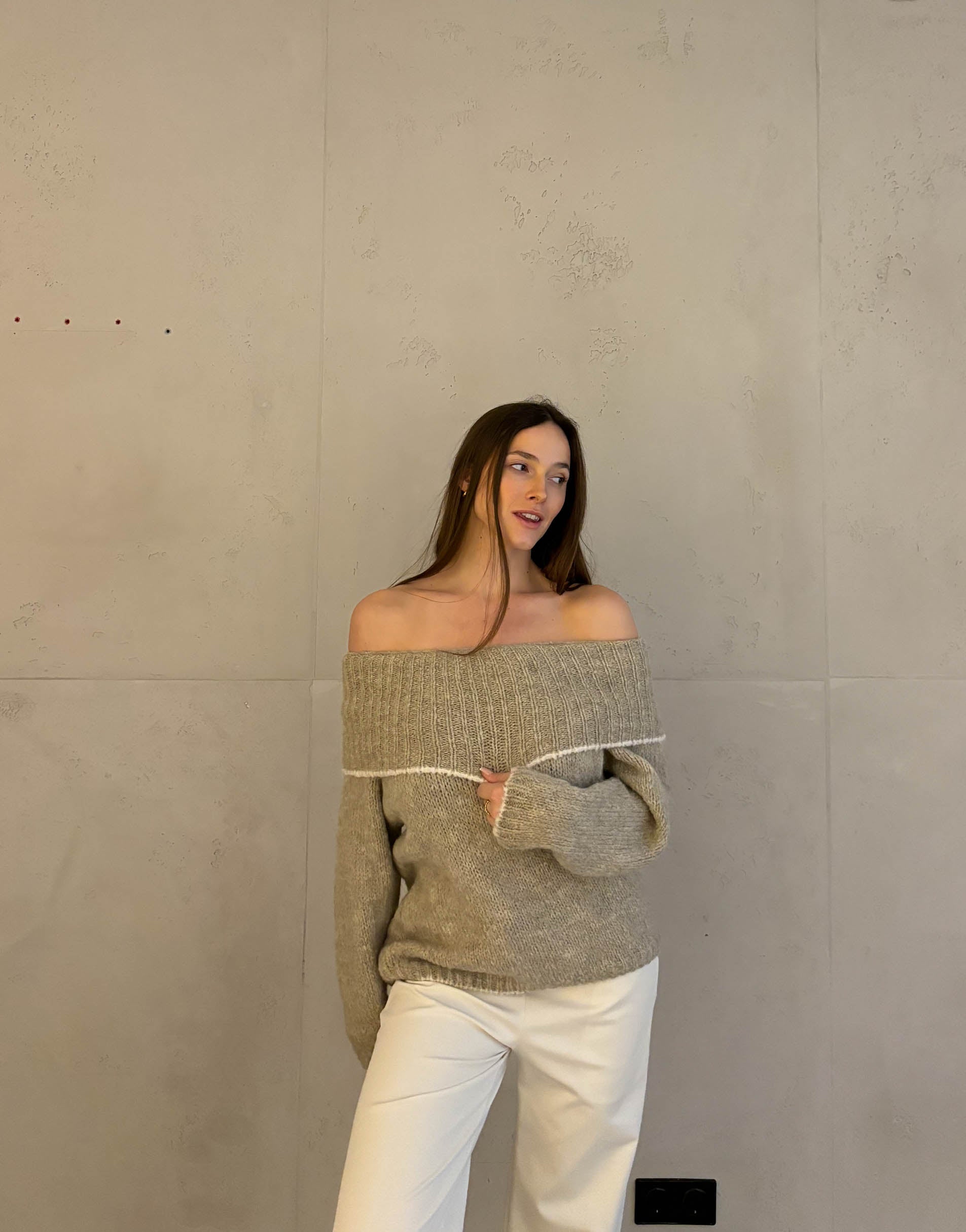 Frau mit brauen Haaren trägt schulterfreien Pullover in taupe