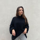 Frau mit brauen Haaren trägt oversize Pullover in Schwarz