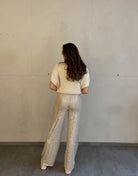Frau mit brauen Haaren trägt Paillettenhose in Beige