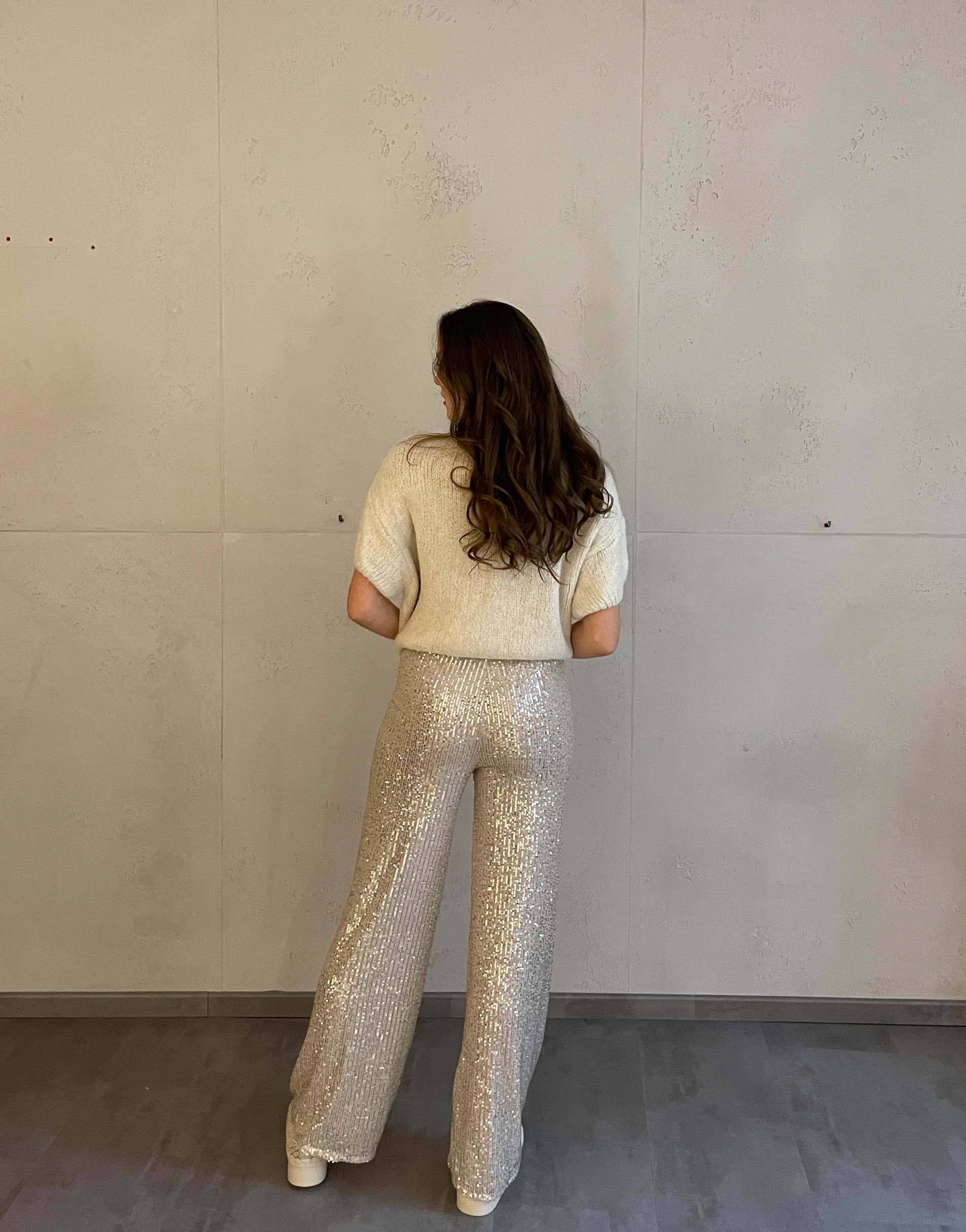 Frau mit brauen Haaren trägt Paillettenhose in Beige
