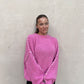 Frau mit brauen Haaren trägt Oversize Pullover in Pink