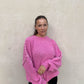 Frau mit brauen Haaren trägt Oversize Pullover in Pink