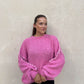 Frau mit brauen Haaren trägt Oversize Pullover in Pink
