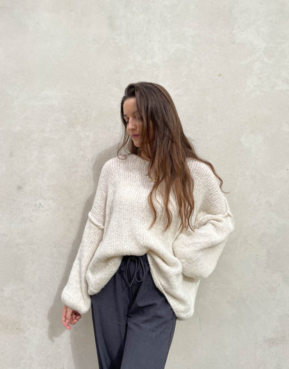 Frau mit brauen Haaren trägt Pullover in beige mit Aussennaht