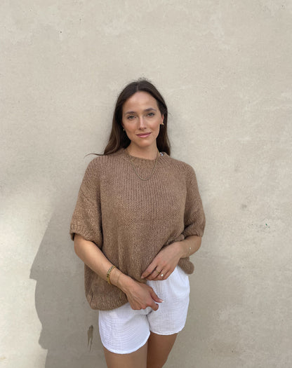 Frau mit brauen Haaren trägt Strickpullover mit Kurzarm in camel