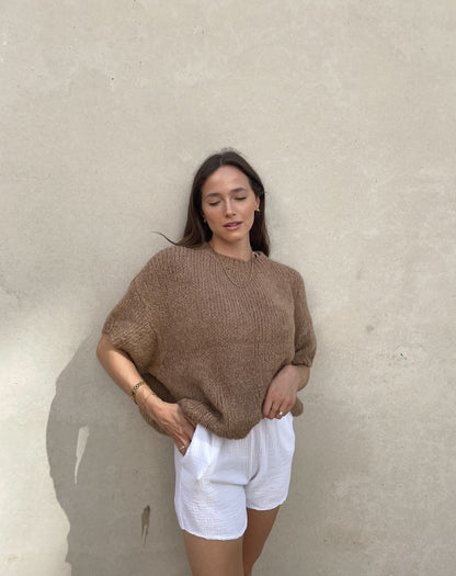 Frau mit brauen Haaren trägt Strickpullover mit Kurzarm in camel