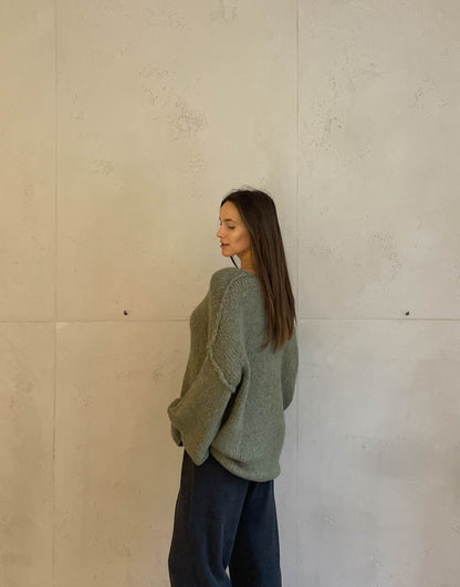 Frau mit brauen Haaren trägt oversize Pullover mit V-Ausschnitt in khaki