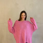 Frau mit brauen Haaren trägt oversize Pullover mit V-Ausschnitt in pink
