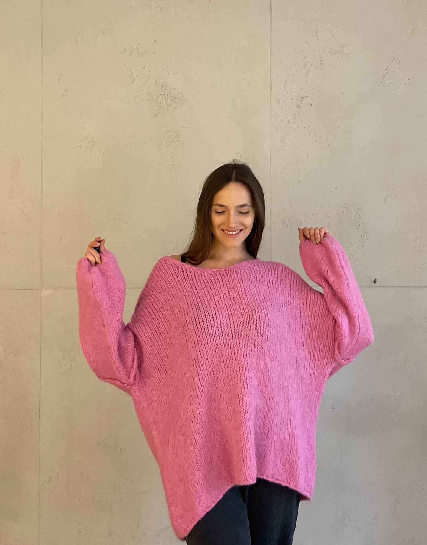 Frau mit brauen Haaren trägt oversize Pullover mit V-Ausschnitt in pink