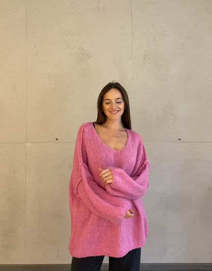 Frau mit brauen Haaren trägt oversize Pullover mit V-Ausschnitt in pink