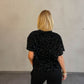 Frau mit blonden Haaren trägt Samt Pailletten T-Shirt in Schwarz