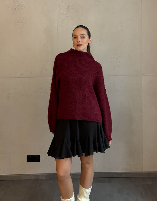 Frau mit braunen Haaren trägt kurzen oversize Pullover mit Stehkragen in Burgundy