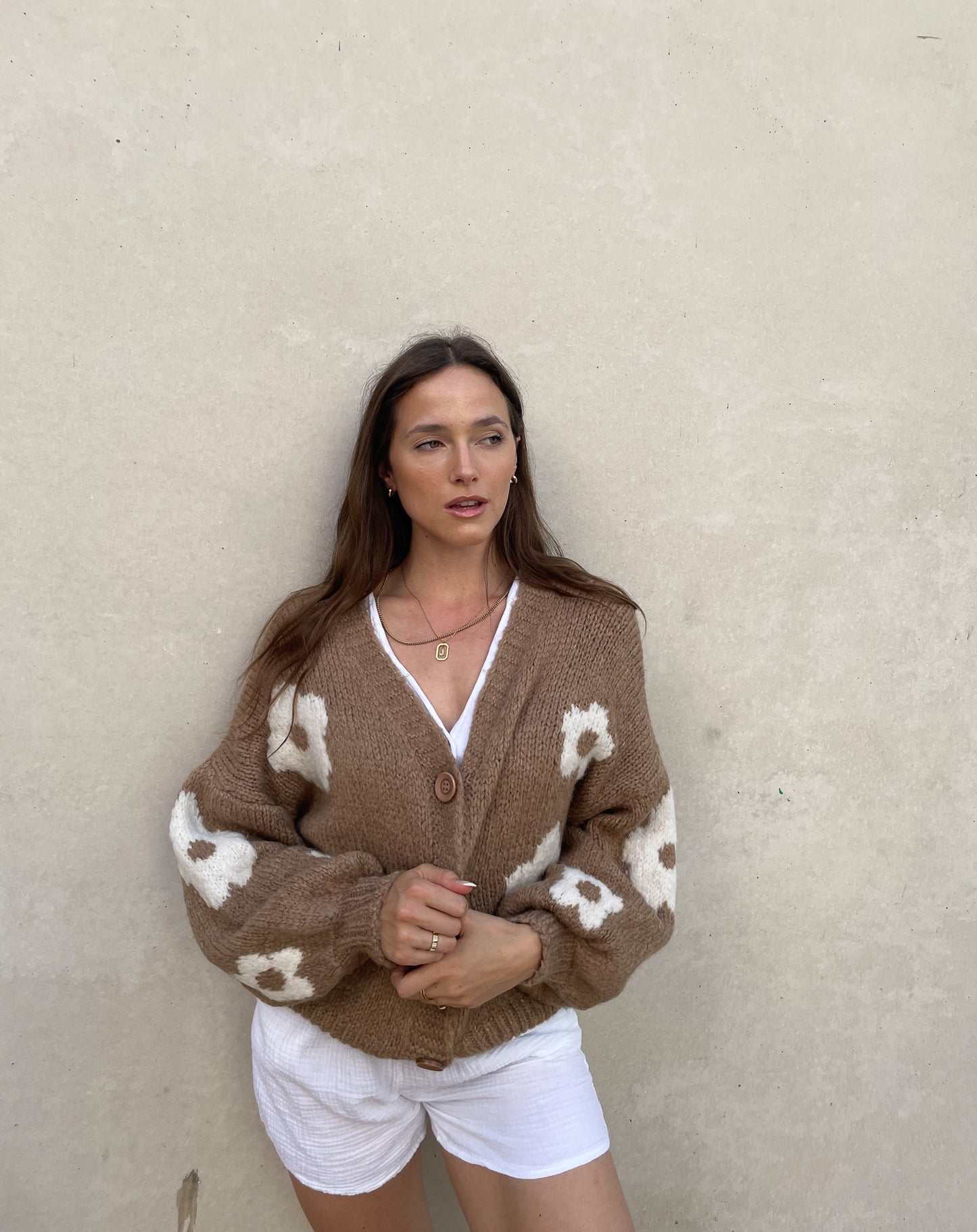 Frau mit brauen Haaren trägt Strickjacke mit Blumenprint