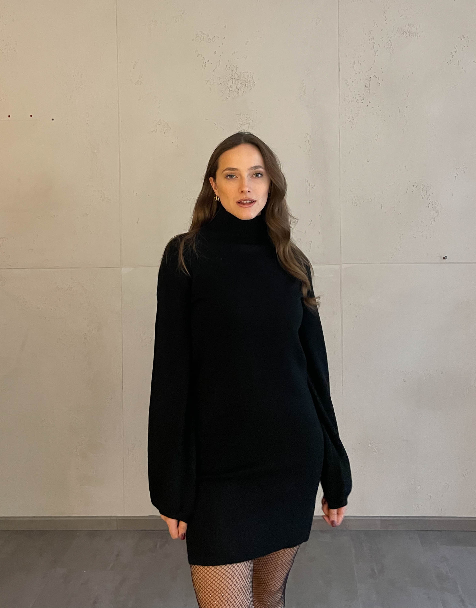 Frau mit brauen Haaren trägt schwarzes Strickkleid in schwarz 