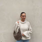 Frau mit brauen Haaren trägt weiten Strickpullover in Beige 