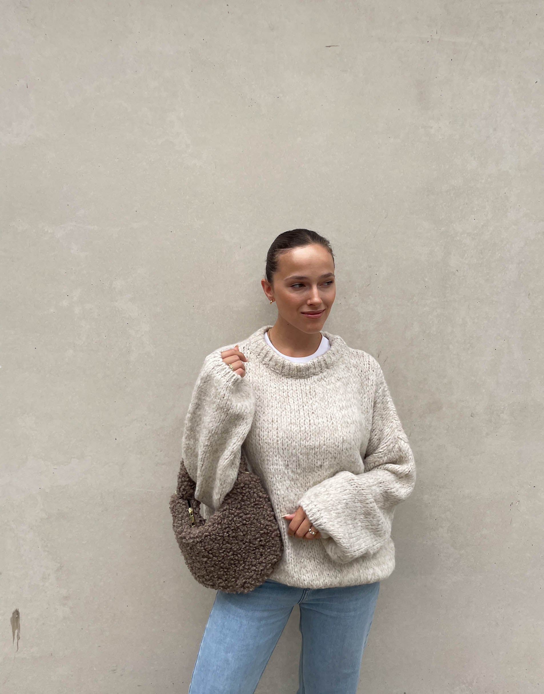 Frau mit brauen Haaren trägt weiten Strickpullover in Beige 