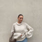 Frau mit brauen Haaren trägt weiten Strickpullover in Beige 