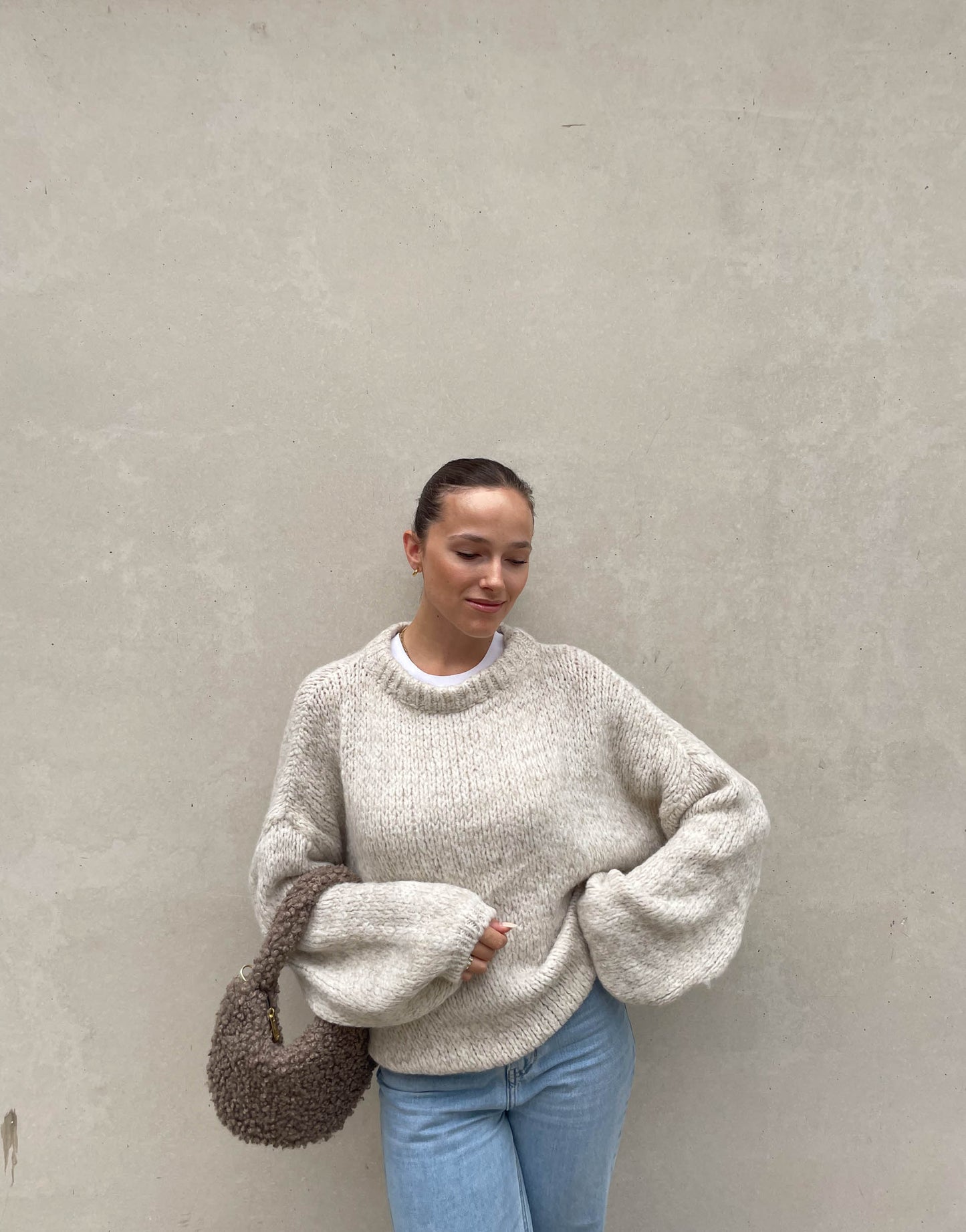 Frau mit brauen Haaren trägt weiten Strickpullover in Beige 