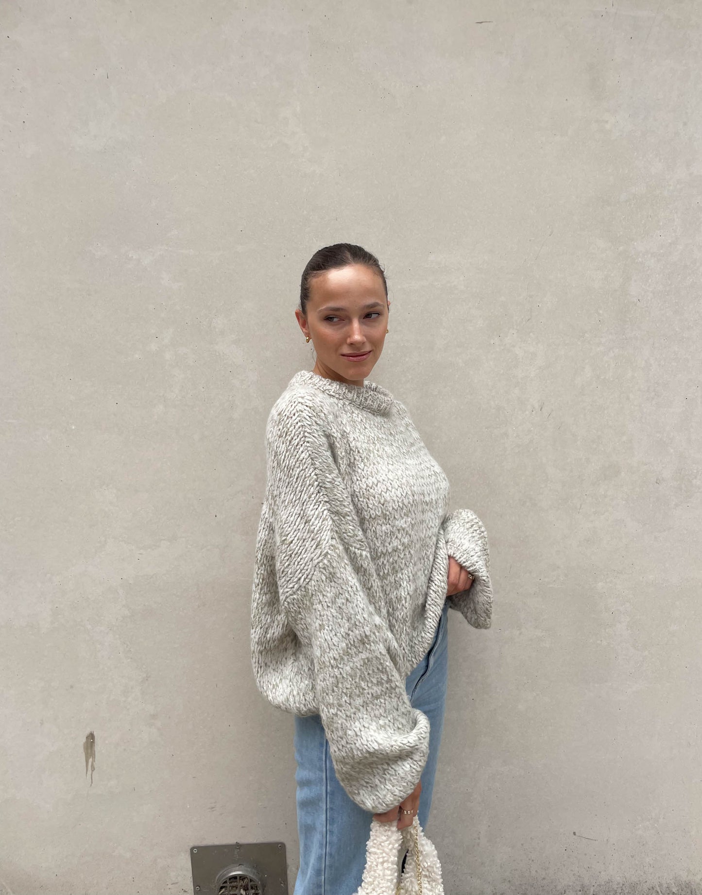 Frau mit brauen Haaren trägt weiten Strickpullover in Mint 