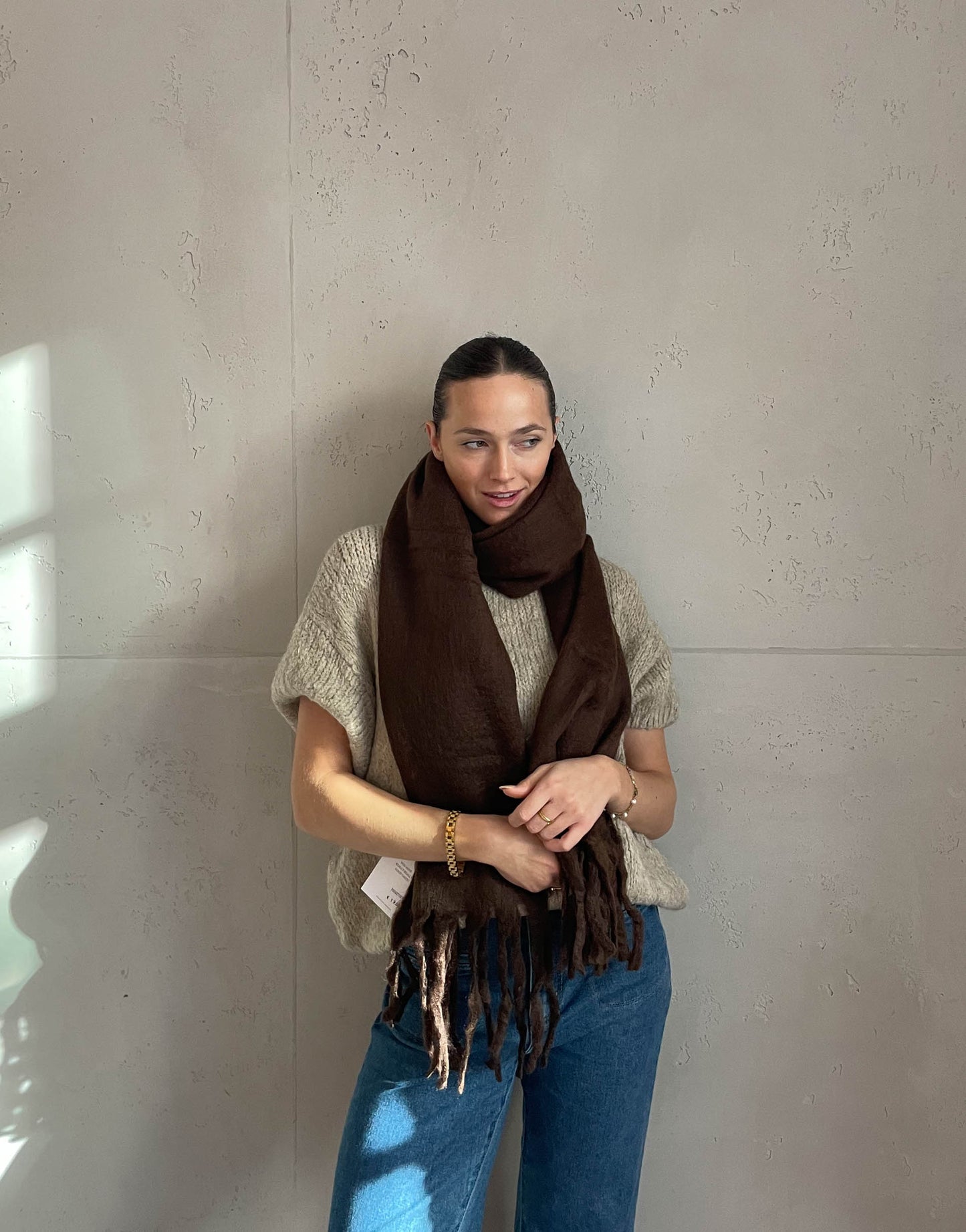 Frau mit brauen Haaren trägt Schal in dunkelbraun